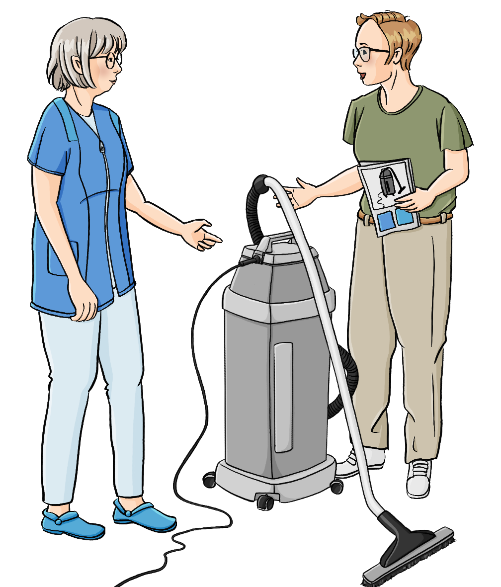 Zwei Frauen weisen auf einen Industriestaubsauger, der zwischen ihnen steht. Die Eine Frau trägt einen Kittel. Die andere Frau trägt Hose und T-shirt. Sie hält ein Heft in der Hand mit dem Bild von einem Staubsauger.