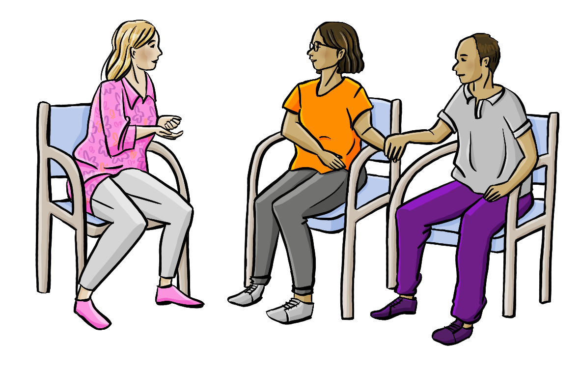 Eine Beraterin, eine Frau und ihr Mann sitzen auf Stühlen. Der Mann und die Frau halten sich an der Hand.