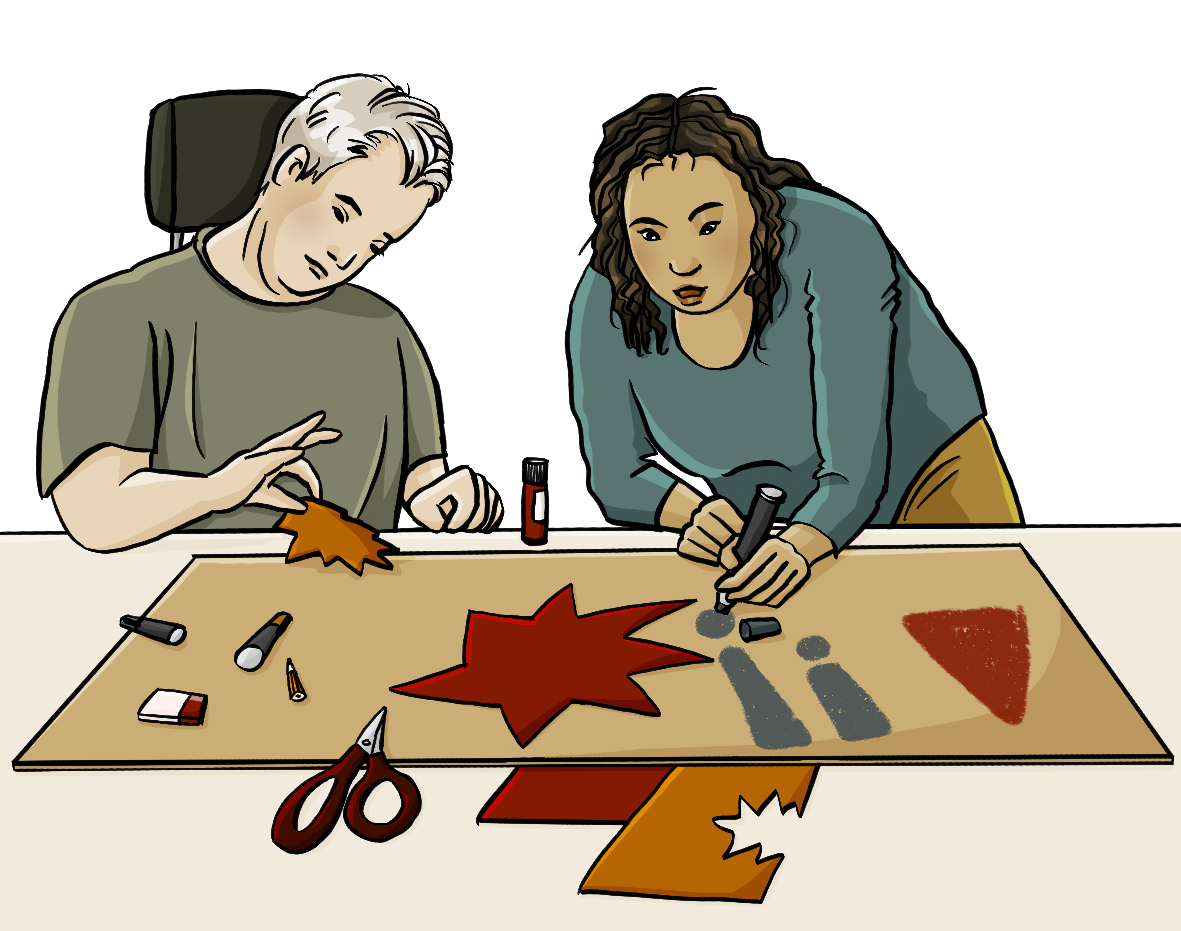 Ein Mann im Rollstuhl und eine Frau hinter einem Tisch. Auf dem Tisch liegen ein großes Stück Pappe und kleinere bunte Papierstücke, eine Schere, Stifte, ein Radiergummi und ein Klebestift. Die Frau schreibt gerade Ausrufezeichen auf das Stück Pappe, der Mann hält ein ausgeschnittes Stück Papier zwischen den Fingern.