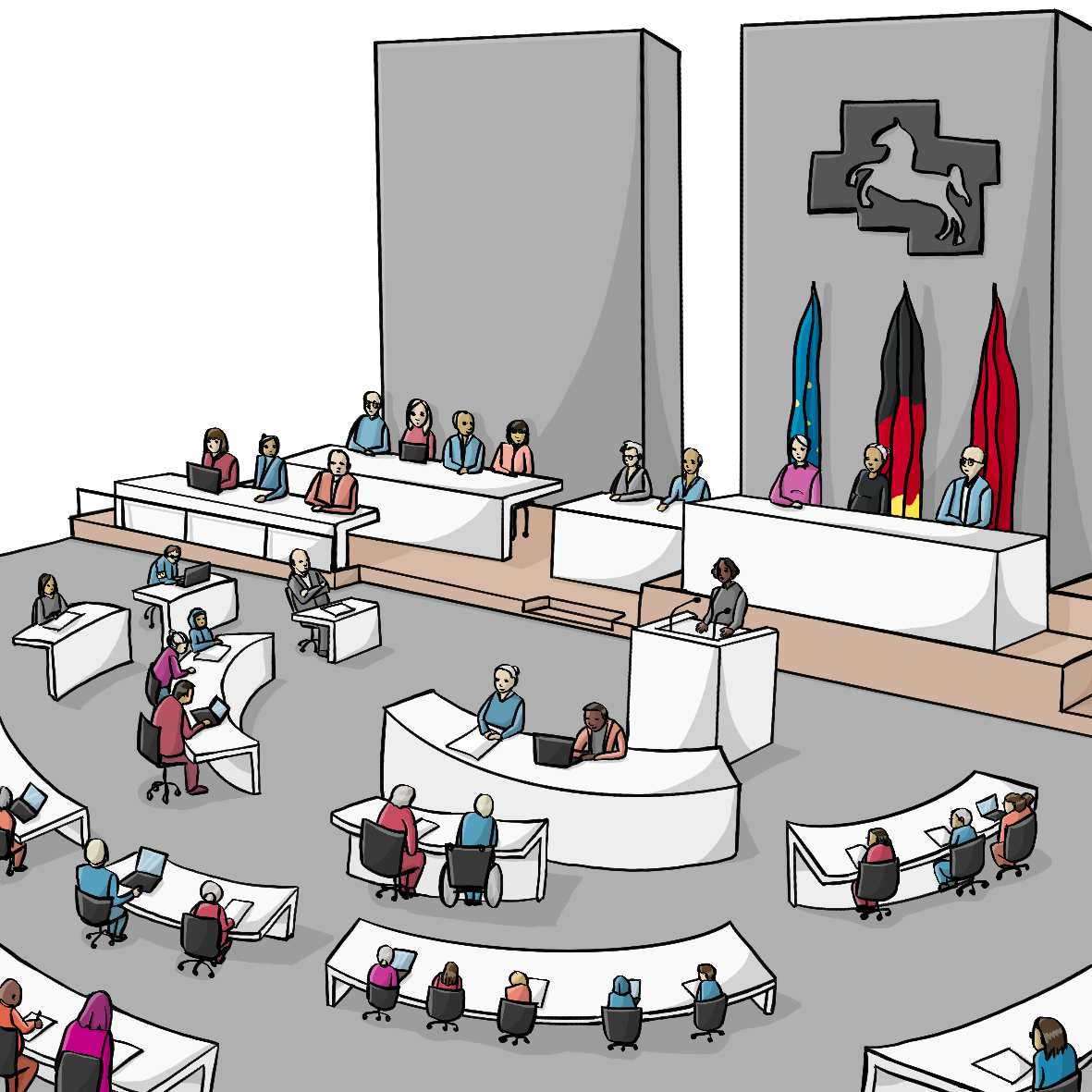 Menschen sitzen an mehreren Reihen bogenförmiger Tische. Vorne steht eine Frau an einem Rednerpult. Hinter der Frau sitzen auf einem Podest Menschen an einer Reihe Tische. Hinter ihnen an der Wand hängen die Fahnen von Europa, Deutschland und Niedersachsen. Darüber hängt eine Metallplatte mit einem Loch in Form eines Pferdes.