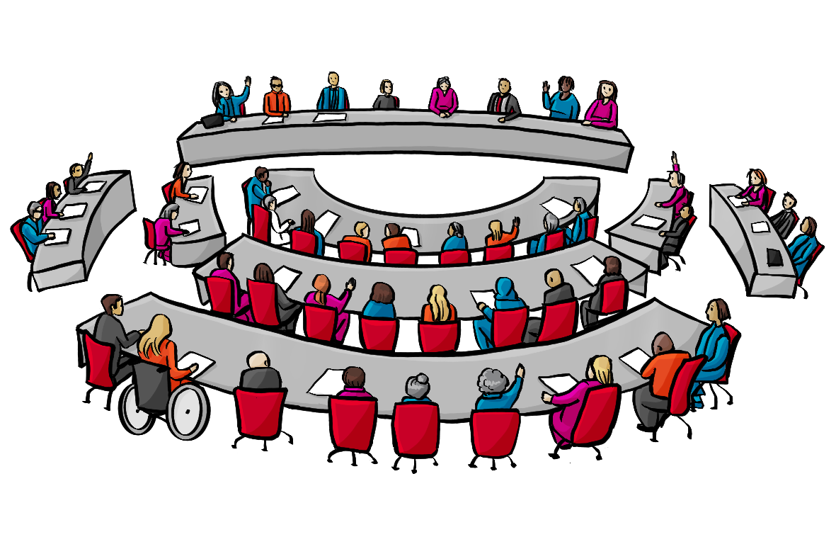 Viele Menschen sitzen an gebogenen Tischreihen. Einige haben die Hand gehoben.