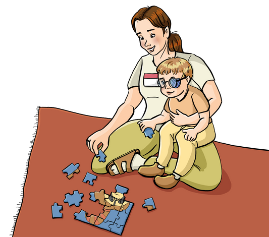 Eine Frau mit Namensschild hat ein Kind auf dem Schoß. Vor ihnen auf dem Teppich liegt ein Puzzle.