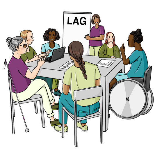 Mehrere Frauen und ein Mann sitzen um einen Tisch herum. Auf dem Tisch sind Zettel und Getränke. Der Mann schreibt an einem Laptop. Eine Frau schreibt auf eine Flipchart. Auf der Flipchart steht LAG.