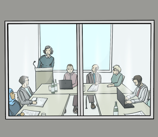 Eine Wand mit einem Fenster. Durch das Fenster sieht man mehrere Menschen an Tischen sitzen. Auf den Tischen sind Laptops und Papiere. Eine Frau hält einen Vortrag.