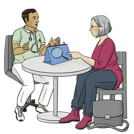 Eine Frau und ein Mann sitzen an einem runden Tisch. Der Mann trägt ein hellgrünes T-Shirt und eine weiße Hose, um seinen Hals hängt ein Stethoskop. Auf dem Tisch steht ein Aufsteller mit einer Lupe. Die Frau zeigt auf den Aufsteller.