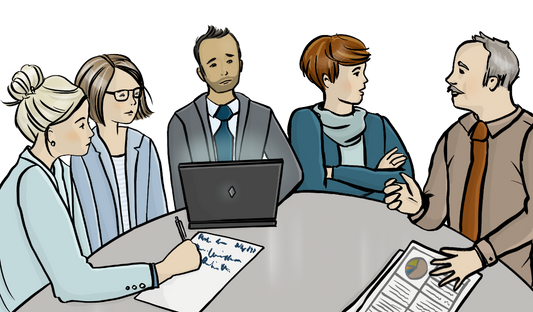 Männer und Frauen sitzen an einem Tisch. Alle sind förmlich gekleidet. Auf dem Tisch sind Papiere und ein Laptop.