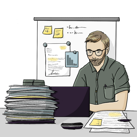 Ein Mann sitzt am Schreibtisch am Laptop. Auf dem Schreibtisch liegen ein Telefon und hohe Papierstapel. Im Hintergrund an der Wand hängt ein Whiteboard mit Notizen und Zetteln.