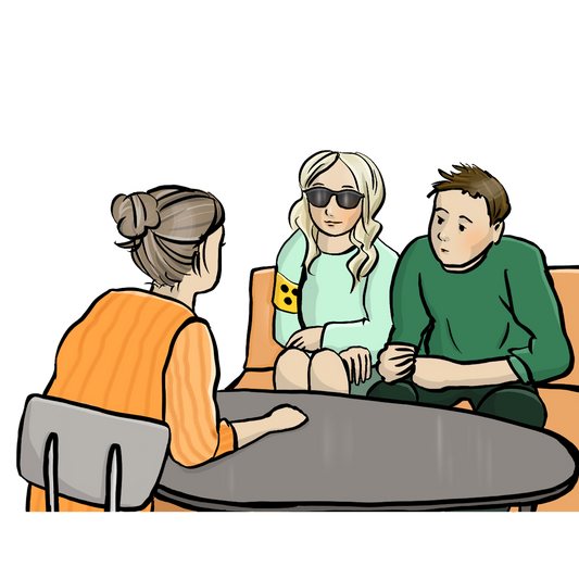 Ein Mann und eine Frau sitzen an einem niedrigen Runden Tisch, die Frau trägt eine Sonnenbrille und eine Blindenbinde. Ihnen gegenüber am Tisch sitzt eine weitere Frau.